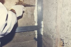 El empleado rellena las grietas en la espuma de construcción de la pared.